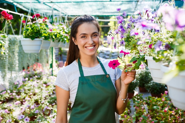 Young beautiful florist posing, smiling among flowers.