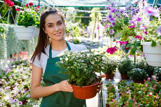 Young beautiful florist posing, smiling among flowers.