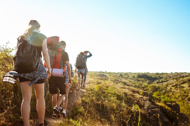 Young beautiful friends travelers with backpacks walking in canyon