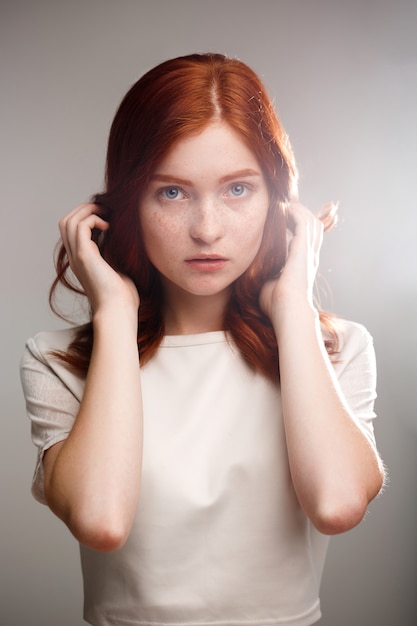 young beautiful ginger girl over gray wall with back light.