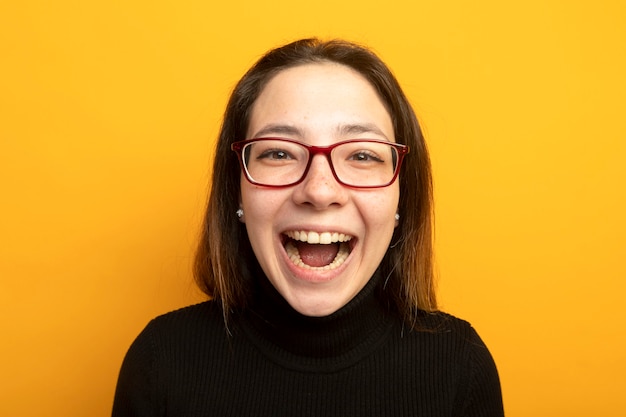 Young beautiful girl in a black turtleneck lookign at camera laughing out 