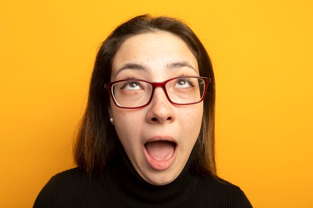 Free photo young beautiful girl in a black turtleneck looking up shouting with annoyed expression