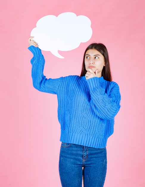 Young beautiful girl holding a white bubble for text on a pink.