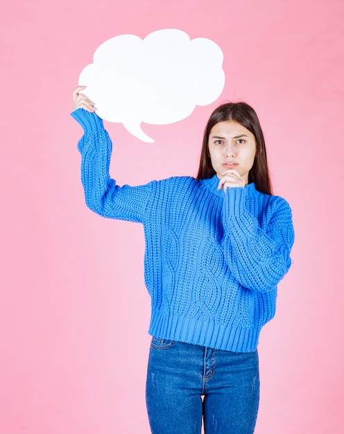 Young beautiful girl holding a white bubble for text on a pink.