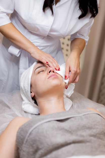 A young beautiful girl lies on the beautician's table and receives procedures, a light facial massage.