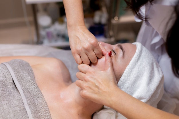 Free Photo a young beautiful girl lies on the beautician's table and receives procedures, a light facial massage.