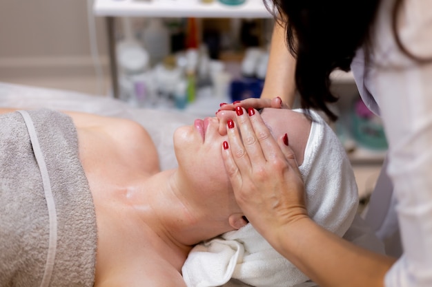 A young beautiful girl lies on the beautician's table and receives procedures, a light facial massage.