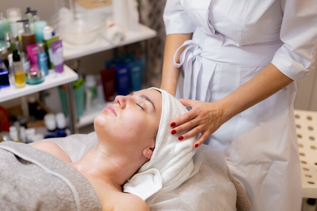 A young beautiful girl lies on the beautician's table and receives procedures, a light facial massage.