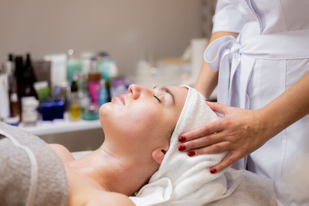 A young beautiful girl lies on the beautician's table and receives procedures, a light facial massage.