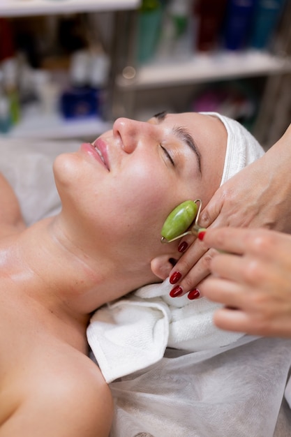 Free photo a young beautiful girl lies on the beautician's table and receives procedures, a light facial massage.