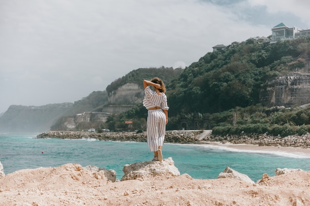 young beautiful girl posing on the beach, ocean, waves, bright sun and tanned skin