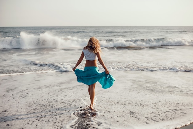 young beautiful girl posing on the beach, ocean, waves, bright sun and tanned skin