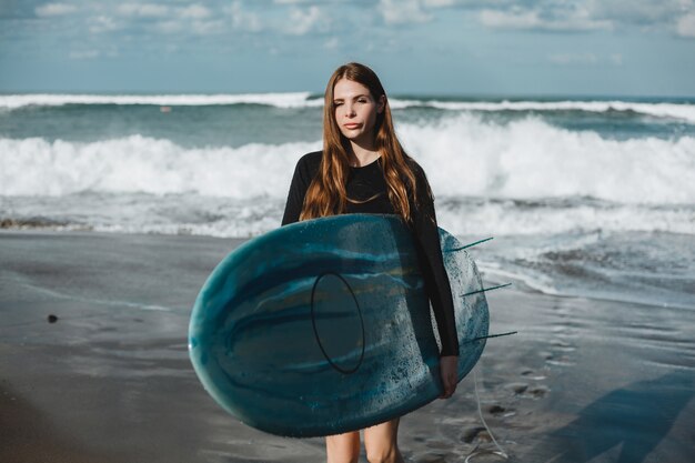 young beautiful girl posing on the beach with a surfboard, woman surfer, ocean waves