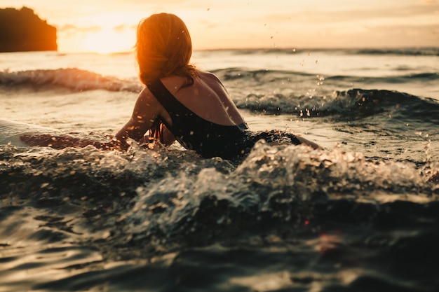 young beautiful girl posing on the beach with a surfboard, woman surfer, ocean waves