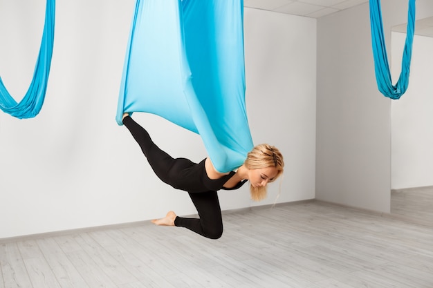 Free photo young beautiful girl practicing aerial yoga in gym.