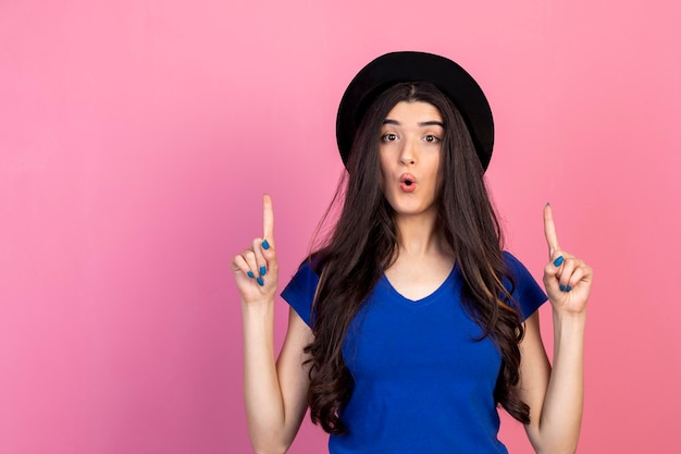 Young beautiful girl raised her finger up and stand on pink background High quality photo