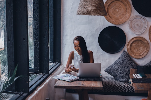 Free photo young beautiful girl uses a laptop in cafe, surfing the internet