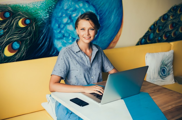 Free photo young beautiful girl uses a laptop in cafe, surfing the internet