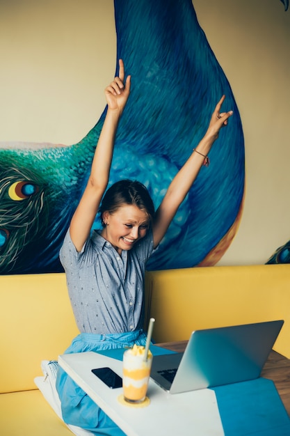 young beautiful girl uses a laptop in cafe, surfing the internet