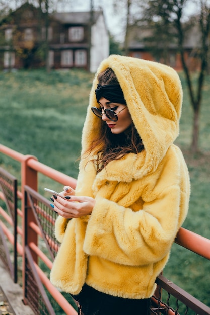 young beautiful girl uses a smartphone on the street, surfing in the internet and drinking coffee