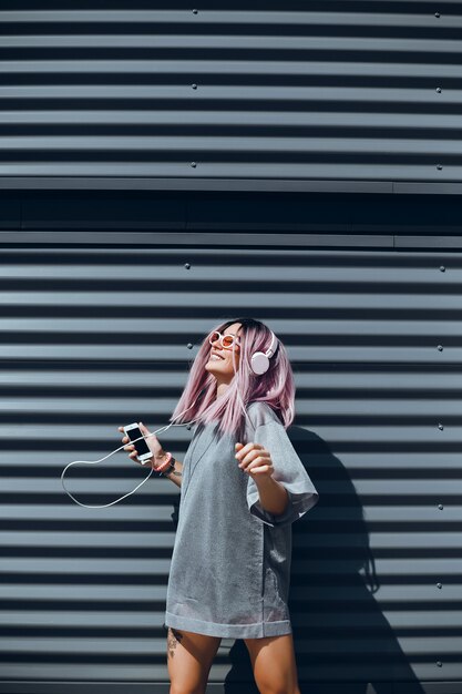 young beautiful girl uses a smartphone on the street, surfing the internet and listening music