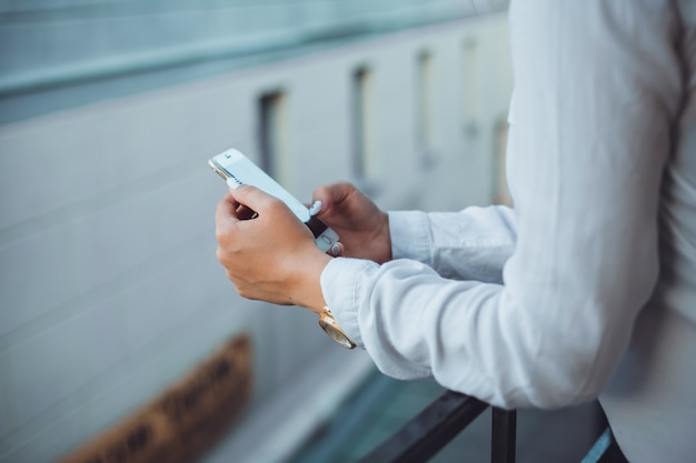 young beautiful girl uses a smartphone on the street, surfing in the internet