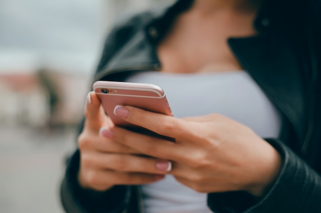 Free photo young beautiful girl uses a smartphone on the street, surfing the internet