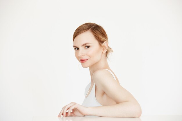 Young beautiful girl with perfect clean skin smiling sitting at table . Beauty spa and cosmetology.