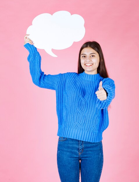 Young beautiful girl with a white bubble for text showing a thumb up.