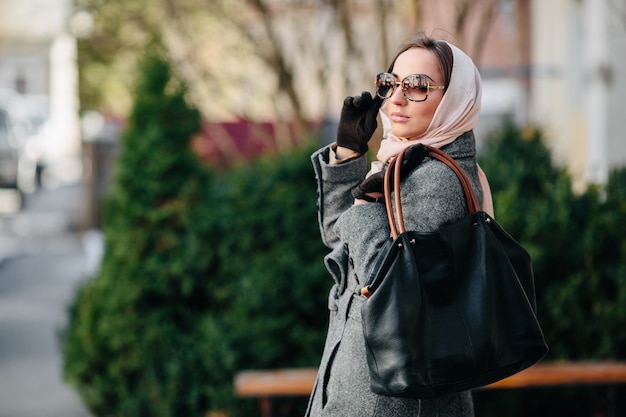 Young beautiful happy woman in a coat posing at the park