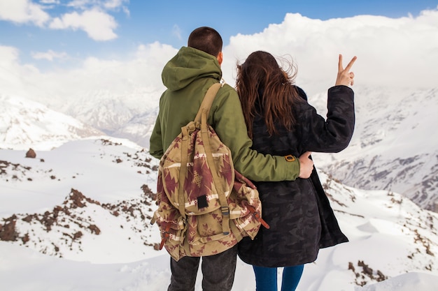 Young beautiful hipster couple hiking in mountains, winter vacation traveling, man woman in love view from back