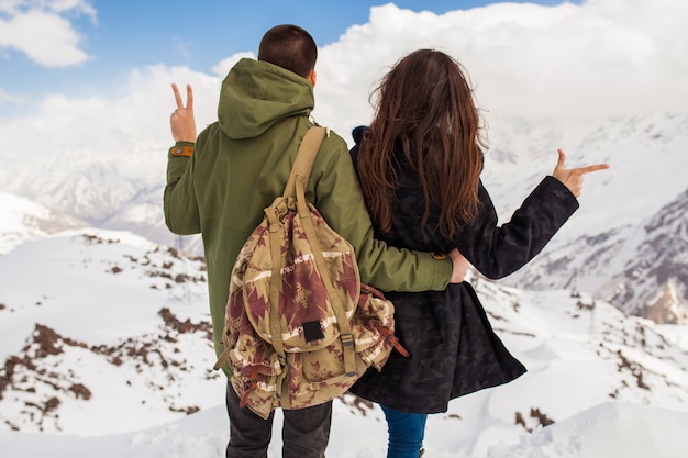 Young beautiful hipster couple hiking in mountains, winter vacation traveling, man woman in love view from back