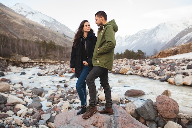 Young beautiful hipster couple in love, walking by the river, wild nature, winter vacation