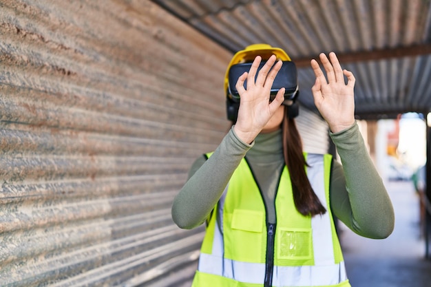 Free photo young beautiful hispanic woman architect using virtual reality glasses at street