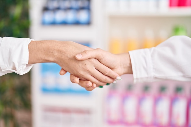 Free Photo young beautiful hispanic woman customer shake hands with pharmacist at pharmacy