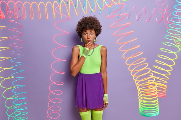 Free Photo young beautiful impressed woman has curly hairstyle, dressed in bright clothes