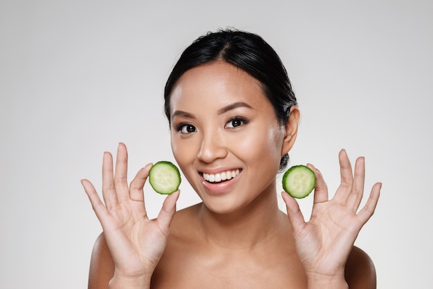 Young beautiful lady holding slices of cucumber