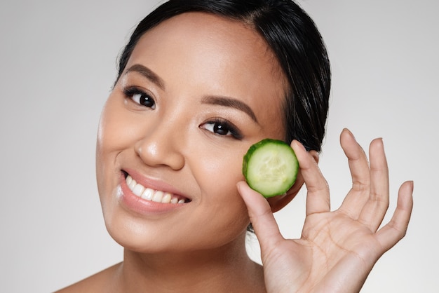 Young beautiful lady holding slices of cucumber