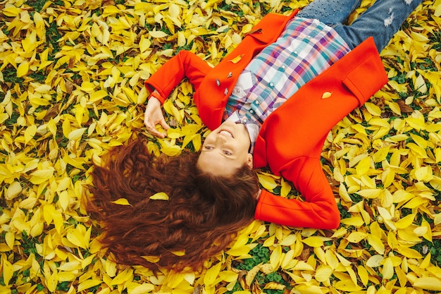 Free photo young beautiful lady surrounded autumn leaves