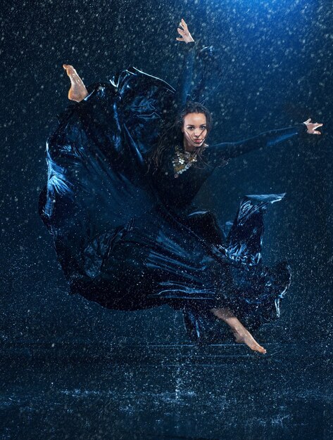 The young beautiful modern dancer dancing under water drops