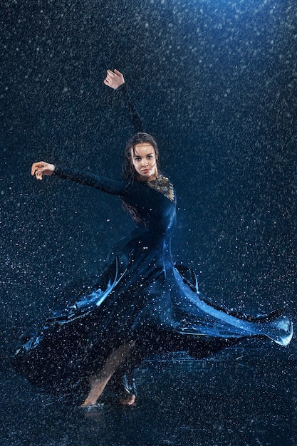 The young beautiful modern dancer dancing under water drops