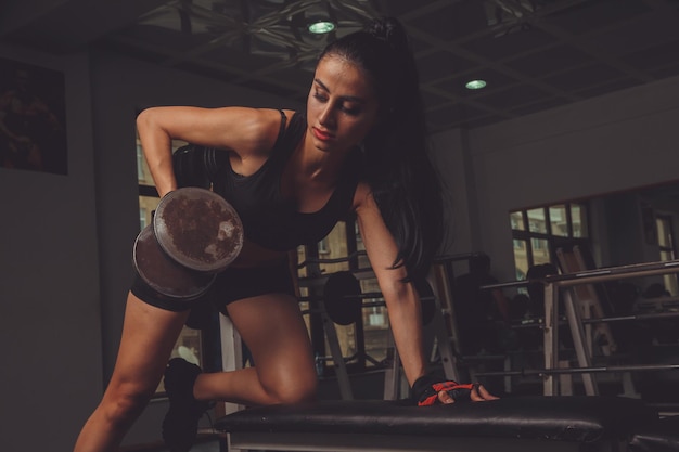 Free photo young beautiful sexy blonde athlete bodybuilder exercises in the gym in beautiful sportswear on a dark background