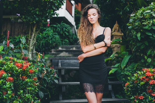 Free photo young beautiful sexy woman in tropical garden, summer vacation in thailand, slim skinny tanned body, little black dress with lace, natural look, sensual, relaxed,