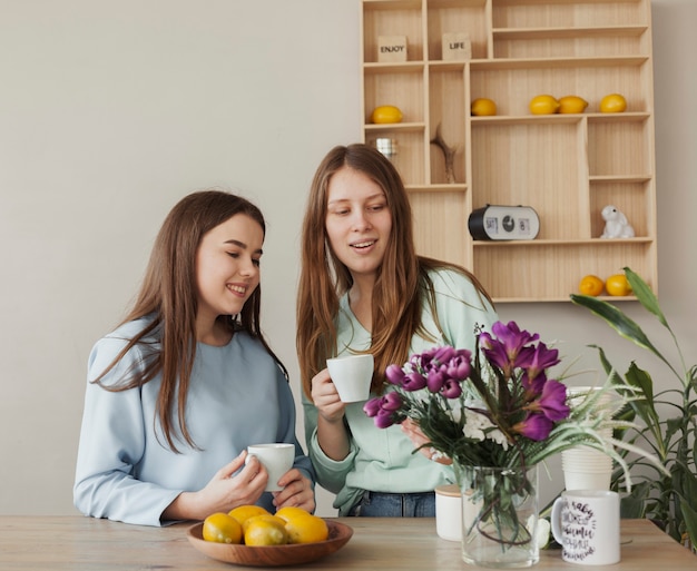 Young beautiful sisters holding white cups