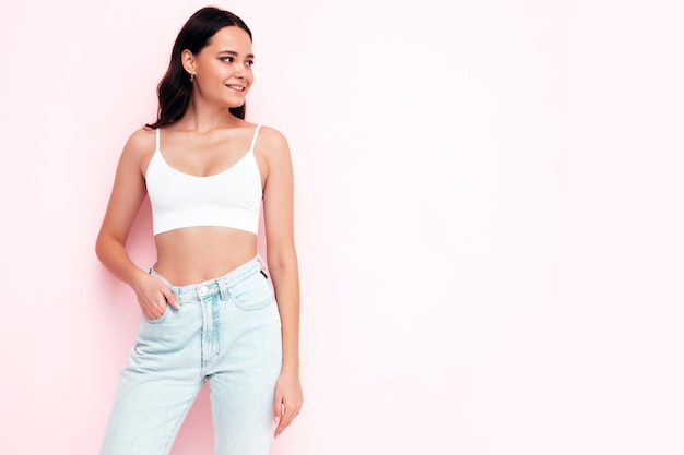 Young beautiful smiling female in trendy summer clothes Sexy carefree woman posing near pink wall in studio Positive brunette model having fun and going crazy Cheerful and happy