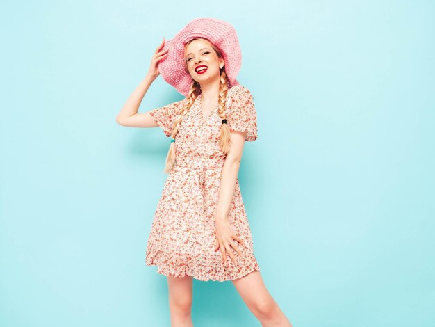 Young beautiful smiling female in trendy summer dress Sexy carefree blond woman posing near blue wall in studio Model having fun Cheerful and happy