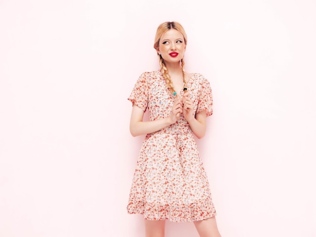 Young beautiful smiling female in trendy summer dress Sexy carefree blond woman posing near wall in studio Model having fun Cheerful and happy