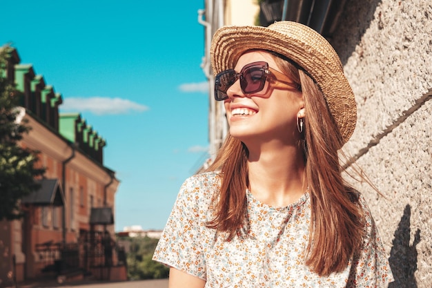 Young beautiful smiling hipster woman in trendy summer clothes Sexy carefree woman posing on the street background at sunset Positive model outdoors Cheerful and happy in sunglasses and hat