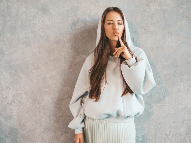 Young beautiful smiling woman looking . Trendy girl in casual summer hoodie and skirt clothes.  Making duck face