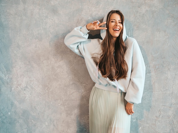 Free photo young beautiful smiling woman looking . trendy girl in casual summer hoodie and skirt clothes.  .shows peace sign